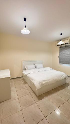1 dormitorio con 1 cama blanca y 2 luces en Chic 3-BR Tala Almajd Villas in upscale district Alnahdah Family only en Yeda