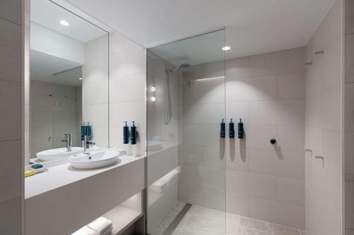 y baño blanco con lavabo y ducha. en DoubleTree by Hilton Esplanade Darwin, en Darwin