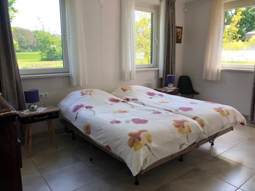 een bed in een slaapkamer met 2 ramen bij De Daalse Oase in Aalten