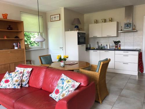 a red couch in a kitchen with a table at De Daalse Oase in Aalten