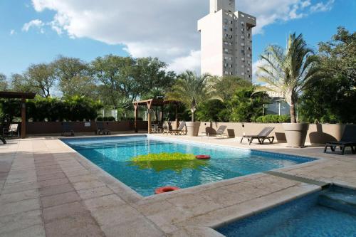 uma piscina com um edifício ao fundo em Wyndham Golden Foz Suítes em Foz do Iguaçu