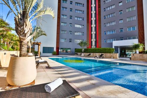 a swimming pool with a palm tree next to a building at Wyndham Golden Foz Suítes in Foz do Iguaçu