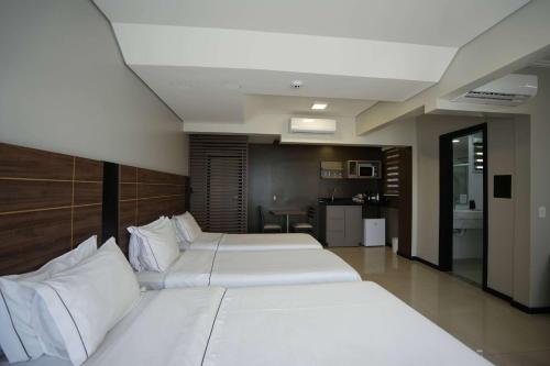 a bedroom with two beds with white pillows at Wyndham Golden Foz Suítes in Foz do Iguaçu