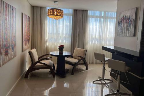 a living room with a table and chairs and a piano at Wyndham Golden Foz Suítes in Foz do Iguaçu