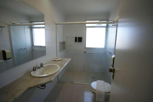 a white bathroom with a sink and a shower at Wyndham Golden Foz Suítes in Foz do Iguaçu