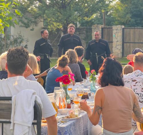 a group of people sitting around a table in a garden at Chubini Winery & Cabins in Kvareli