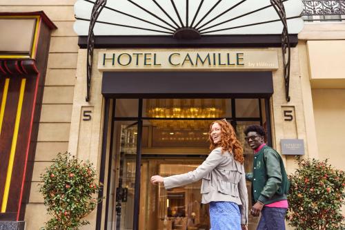 un homme et une femme debout devant un hôtel camille dans l'établissement Hotel Camille Paris Tapestry Collection by Hilton, à Paris
