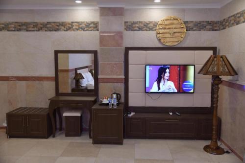 a living room with a television and a mirror at Parezh Hotel in As Sulaymānīyah