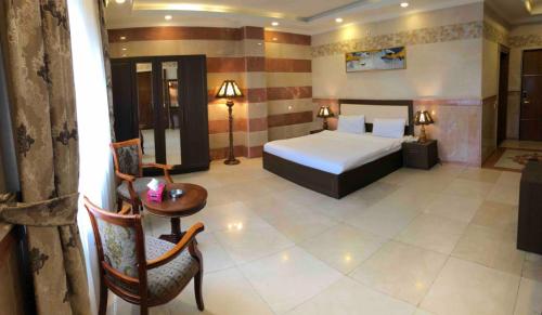 Prizh Hotel في السليمانية: غرفة فندقية بسرير وطاولة وكراسي
