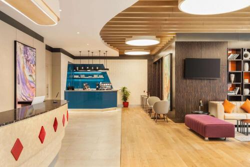 an office lobby with a bar and a tv at Ramada Encore Al Khobar Corniche in Al Khobar