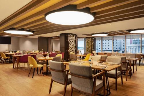 a dining room with tables and chairs and windows at Ramada Encore Al Khobar Corniche- رمادا أنكور الخبر كورنيش in Al Khobar