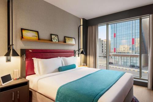 um quarto de hotel com uma cama e uma grande janela em Ramada Encore Al Khobar Corniche- رمادا أنكور الخبر كورنيش em Al Khobar