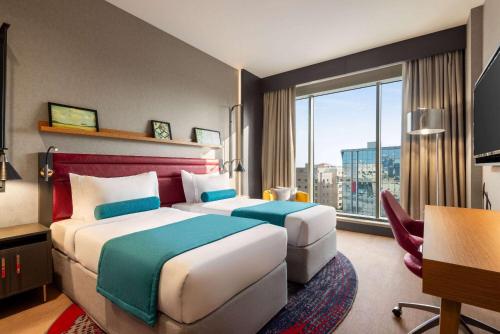 a hotel room with two beds and a large window at Ramada Encore Al Khobar Corniche in Al Khobar