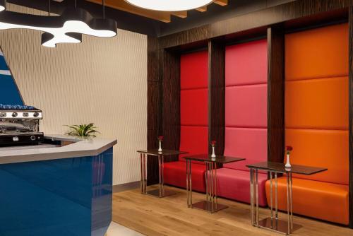 a kitchen with two tables and a red bench at Ramada Encore Al Khobar Corniche in Al Khobar
