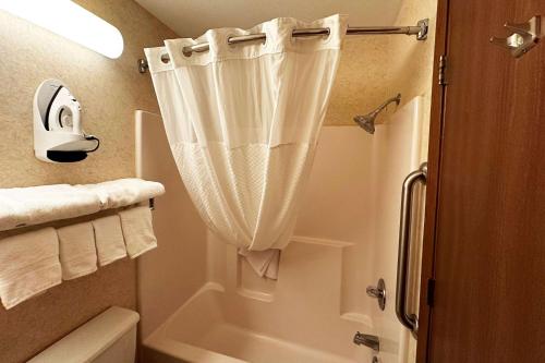 a bathroom with a shower curtain next to a tub at Travelodge by Wyndham Rapid City - Black Hills in Rapid City