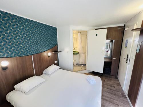 a bedroom with a white bed and a blue wall at Kyriad Direct Val de Reuil in Val de Reuil