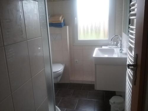La salle de bains est pourvue d'un lavabo, de toilettes et d'une fenêtre. dans l'établissement Komfort 4 Sterne Wohnung " Flut " für 4 Erw Kleinkind in Ostfriesland, à Utarp