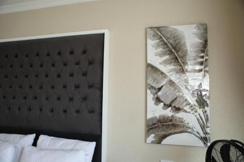 a picture hanging on a wall next to a bed at The Edge Lodge in Polokwane