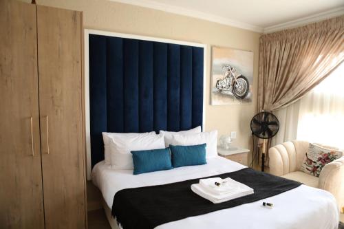 a bedroom with a large bed with a blue headboard at The Edge Lodge in Polokwane