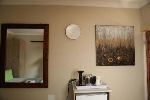 a mirror on a wall next to a counter with a coffee maker at The Edge Lodge in Polokwane