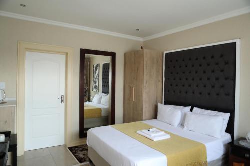 a bedroom with a large white bed and a mirror at The Edge Lodge in Polokwane