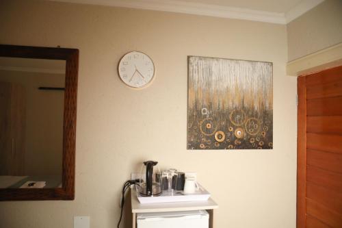 a wall with a clock and a mirror on a wall at The Edge Lodge in Polokwane
