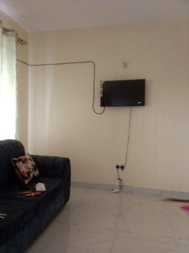 sala de estar con sofá y TV en la pared en Happy Suites, en Mombasa