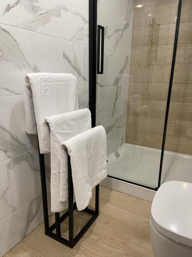 a bathroom with a shower and white towels on a rack at Apartament Rose Valley Dwa Zero in Szczytna