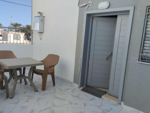 una puerta a un patio con mesa y sillas en Résidence djerba 4, en Houmt El Souk