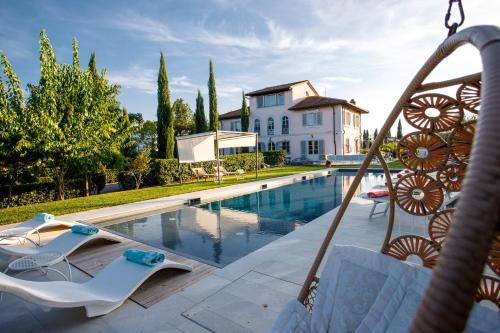 a swimming pool with chairs and a house at Villa Montefalcone: Charm, Private Pool, and Chef in Orentano