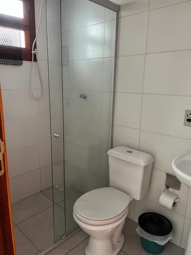 a bathroom with a toilet and a glass shower at Apartamentos Pura Vida em Atlântida Sul in Xangri-lá