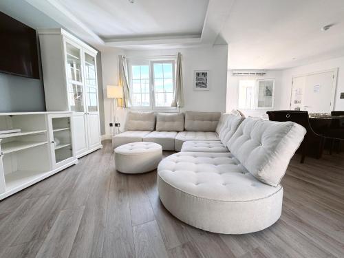 a white living room with a white couch and a tv at Grand Central House - Luxe Penthouse Two Bedroom - GibraltarStay Apartments in Gibraltar