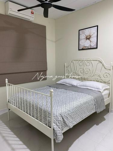 Najma guest house في Kota Bharu: سرير أبيض في غرفة بها مروحة سقف