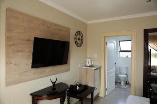 a living room with a flat screen tv on the wall at The Edge Lodge in Polokwane