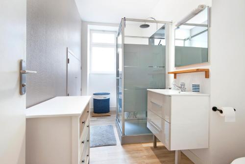une salle de bain avec une douche, un lavabo et un miroir dans l'établissement Appartement Le Pouliguen Centre, au Pouliguen