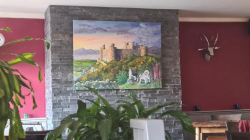 a painting of a castle is hanging on a wall at Y Branwen Restaurant & Rooms - Adult Only and Dog Friendly in Harlech