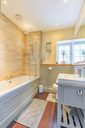 a bathroom with a tub and a toilet and a sink at Dibley Cottage Mundesley in Mundesley