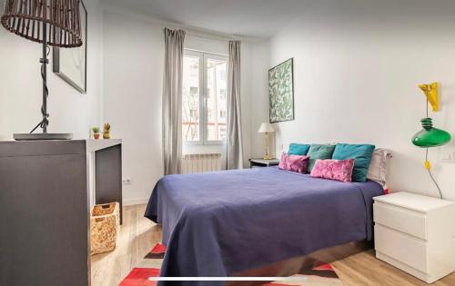 a bedroom with a blue bed with pink and blue pillows at Habitación Simple en PISO COMPARTIDO C in Madrid