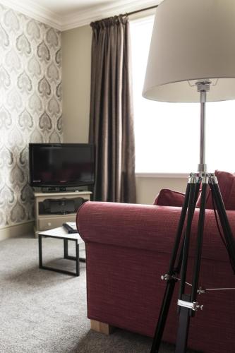 a living room with a red couch and a television at Virginia Court Hotel in Cromer