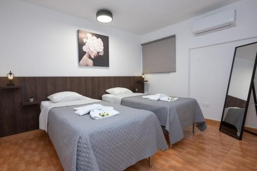 a room with two beds and a white wall at Napa Centrale Suites in Ayia Napa