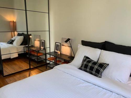 une chambre avec un lit blanc et un miroir dans l'établissement Appartement 3 chambres Paris 7e, à Paris