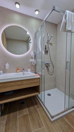 ein Bad mit einer Dusche, einem Waschbecken und einem Spiegel in der Unterkunft Vuk Vučko in Jahorina