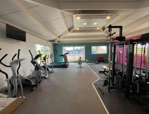 a gym with cardio equipment and a woman in the background at Camping Sable du Midi MH 6-8 personnes in Valras-Plage