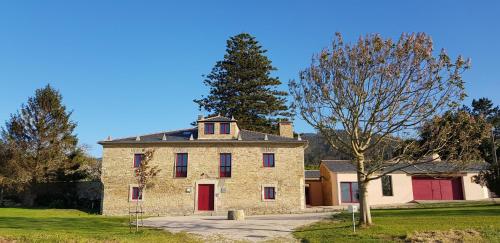 an old stone house with a red door and a tree at Araucaria House in Barreiros