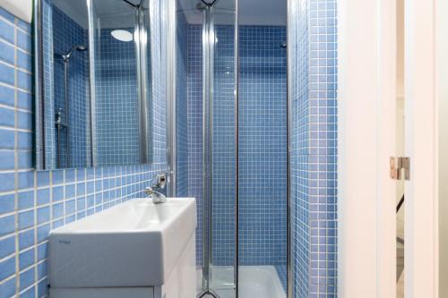 een blauwe betegelde badkamer met een wastafel en een douche bij TravelingToLisbon 98 - Alfama in Lissabon