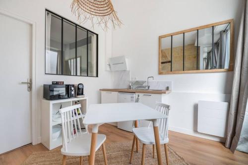 une cuisine avec une table blanche et deux chaises dans l'établissement Le Bordeaux: Joli appartement climatisé proche gare, à Bordeaux