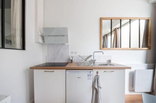 une cuisine blanche avec un évier et un miroir dans l'établissement Le Bordeaux: Joli appartement climatisé proche gare, à Bordeaux