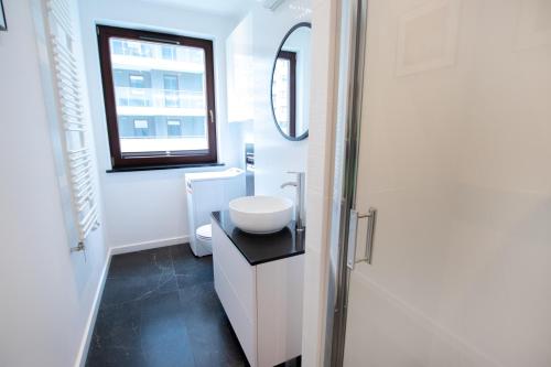 a white bathroom with a sink and a window at High Standard studio. City Center. Free parking. in Warsaw