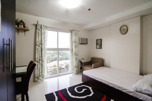 a bedroom with a bed and a window and a desk at 8C Studio Unit with Free Wifi Pool and Gym in Mandaue City