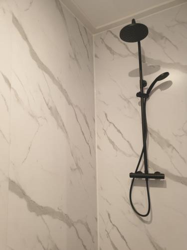a shower with a black shower head on a marble wall at @Salland in Zwolle